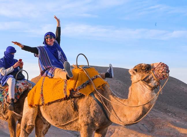 Travelers riding camels in Marrakech Palmeraie