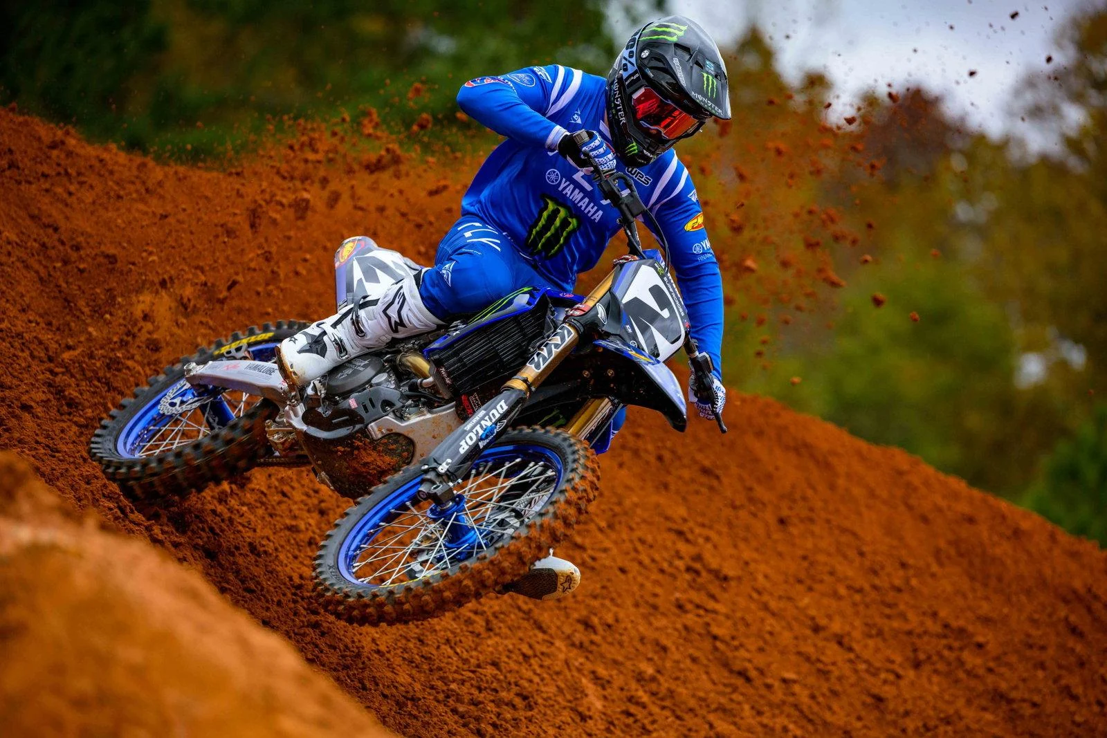 Motocross rider crossing a red dirt track